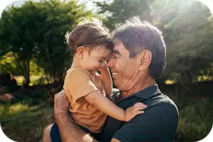 Grandfather holding his grandson in the backyard.