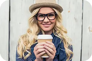 Smiling young woman with a cup of tea and a cute hat.