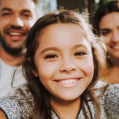 Smiling young girl taking a selfie with her mom and dad.