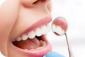Dentist looking at a patients teeth with a small mirror.