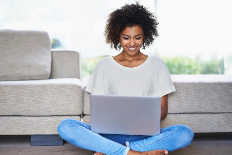 Woman reviewing dental plan options on her laptop leaning against the couch.